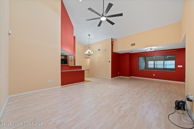 unfurnished living room with baseboards, high vaulted ceiling, wood finished floors, and ceiling fan with notable chandelier