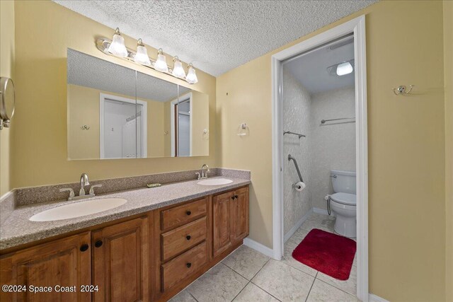 bathroom featuring toilet, a textured ceiling, vanity, and tile patterned floors