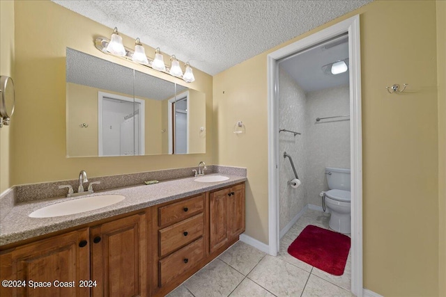 full bath featuring double vanity, toilet, a textured ceiling, and a sink