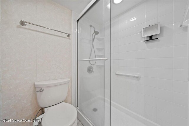 bathroom featuring walk in shower and toilet