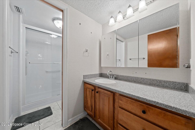 bathroom with vanity, visible vents, a stall shower, a textured ceiling, and tile patterned floors