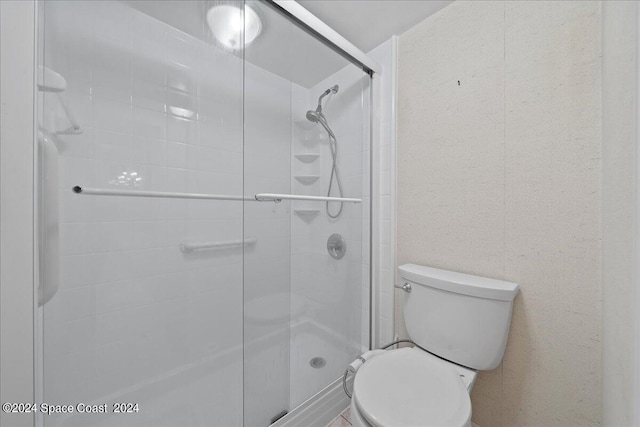 bathroom featuring toilet and a shower with door