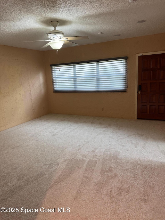 unfurnished room featuring ceiling fan, carpet floors, and a textured ceiling