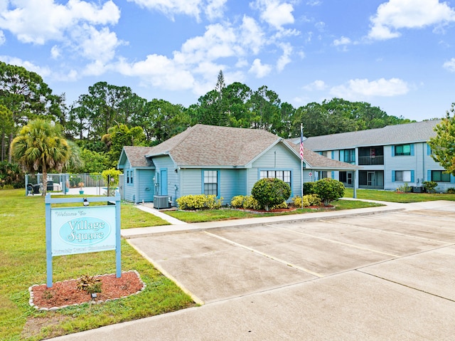 view of front of home featuring cooling unit and a front yard