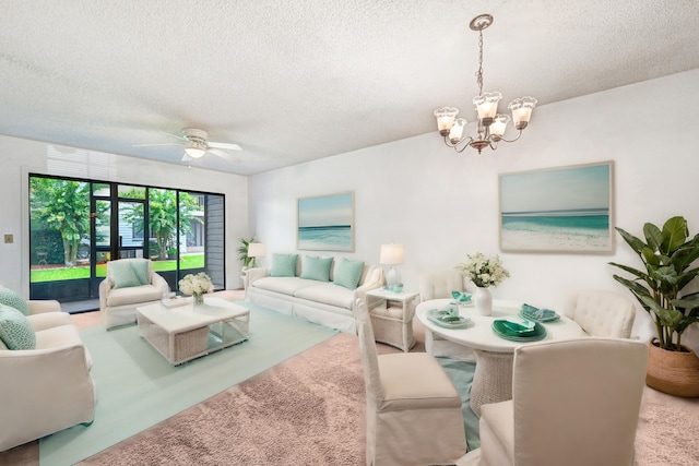 living room featuring a textured ceiling and ceiling fan with notable chandelier