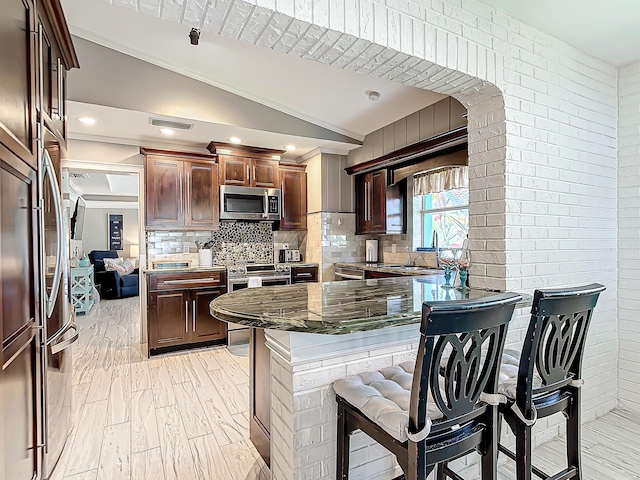 kitchen featuring lofted ceiling, sink, appliances with stainless steel finishes, light hardwood / wood-style floors, and decorative backsplash