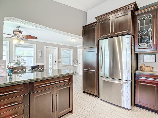 kitchen with dark brown cabinetry, stone countertops, light hardwood / wood-style flooring, stainless steel fridge, and ceiling fan