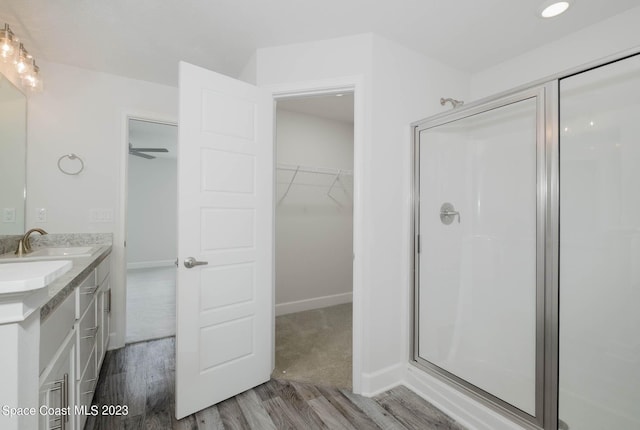 bathroom with ceiling fan, vanity, a shower with door, and hardwood / wood-style flooring