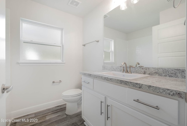 bathroom featuring toilet, vanity, and hardwood / wood-style floors