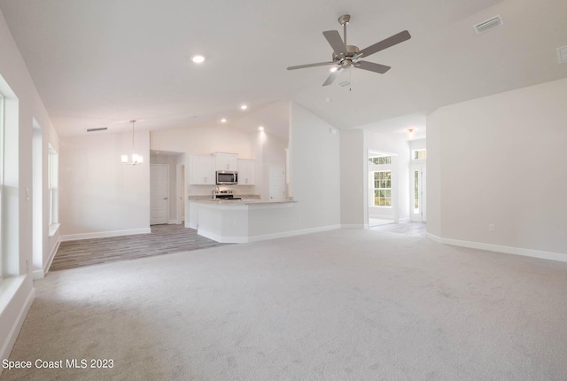 unfurnished living room featuring high vaulted ceiling, light colored carpet, and ceiling fan with notable chandelier