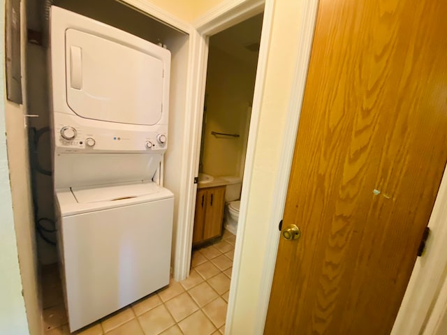 washroom featuring stacked washer and dryer and light tile patterned floors