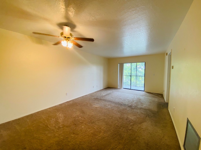 empty room with a textured ceiling, ceiling fan, and carpet