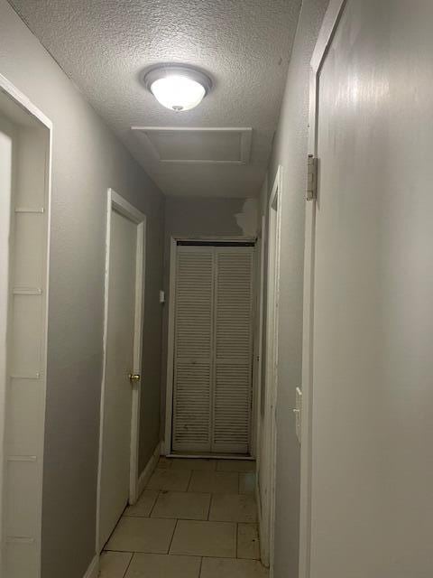 hall featuring light tile patterned flooring and a textured ceiling