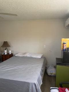 bedroom with a wall mounted air conditioner and a textured ceiling