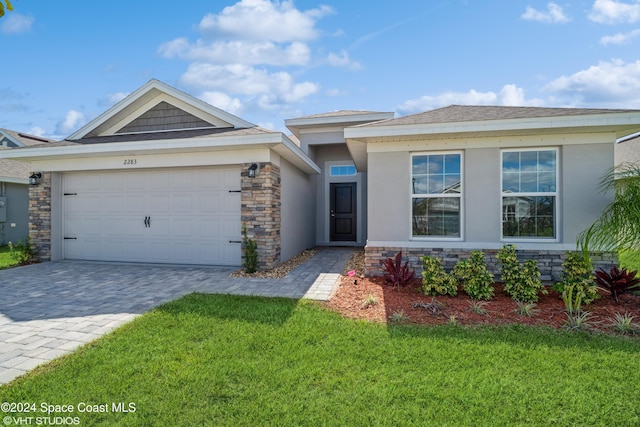 2283 Middlebury Dr SE, Palm Bay, FL 32909 - view of front of property featuring stone siding, decorative driveway, stucco siding, and a front yard