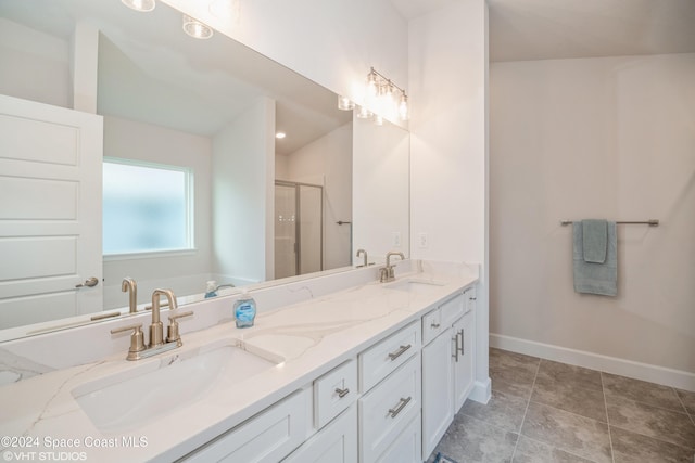 full bath featuring double vanity, a stall shower, baseboards, and a sink