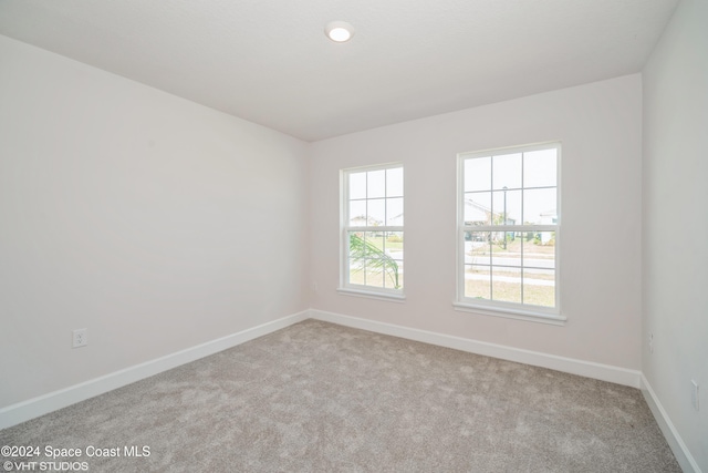 unfurnished room with light colored carpet and baseboards