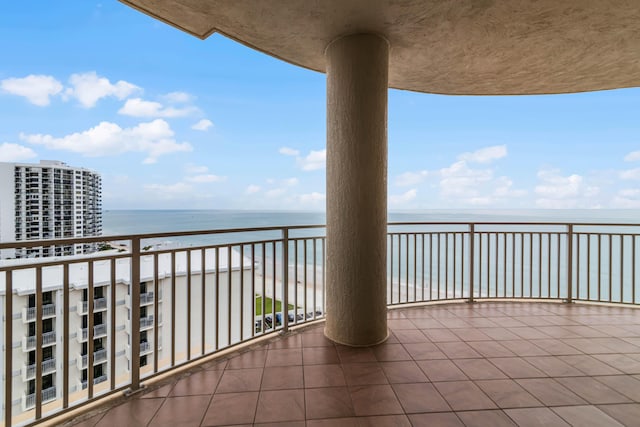 balcony with a water view and a view of the beach