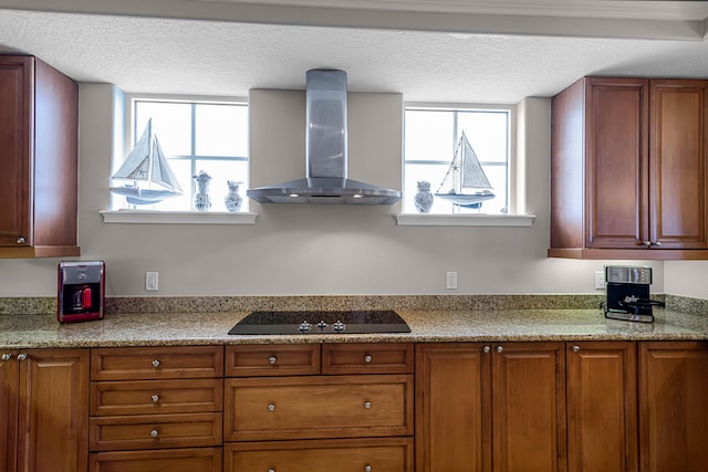 kitchen featuring black electric stovetop, light stone countertops, wall chimney range hood, and a textured ceiling