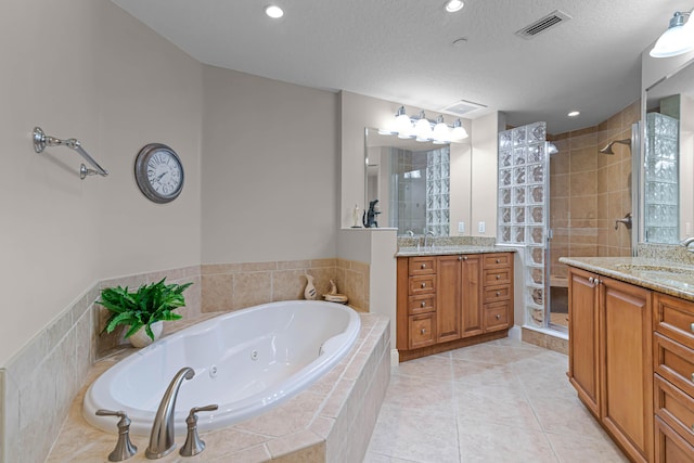 full bathroom featuring visible vents, a shower stall, a sink, and two vanities