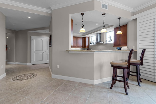 kitchen featuring crown molding, wall chimney range hood, baseboards, and visible vents