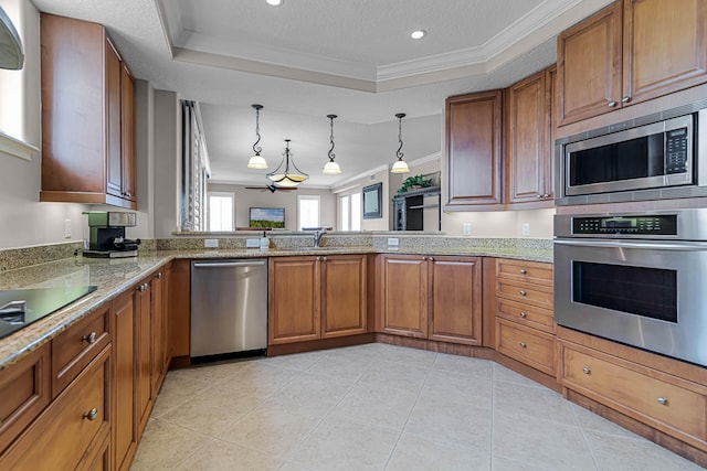 kitchen featuring a tray ceiling, stainless steel appliances, brown cabinets, and ornamental molding