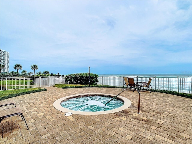 view of swimming pool featuring a patio area, fence, a water view, and a hot tub