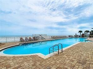 community pool with a patio, a water view, and fence