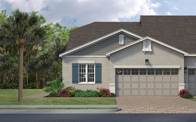 view of front of house featuring stucco siding, roof with shingles, an attached garage, decorative driveway, and a front yard