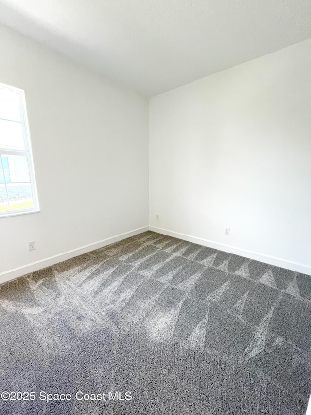 empty room with baseboards and dark carpet