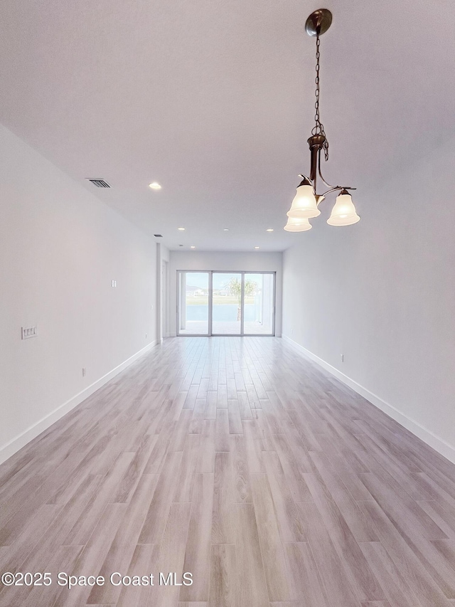 empty room featuring visible vents, light wood-style flooring, and baseboards