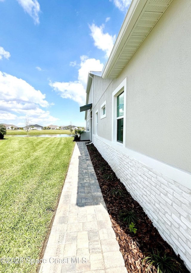 view of property exterior featuring brick siding, a lawn, and stucco siding