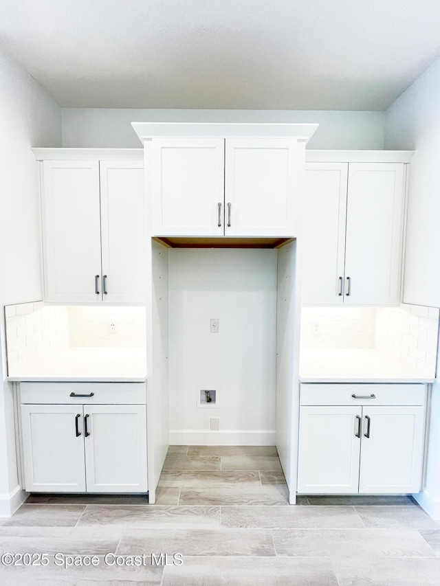 washroom with washer hookup, wood finish floors, cabinet space, and baseboards