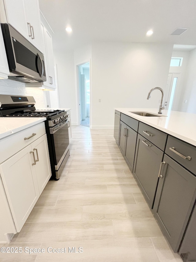 kitchen with backsplash, stainless steel appliances, a sink, and light countertops