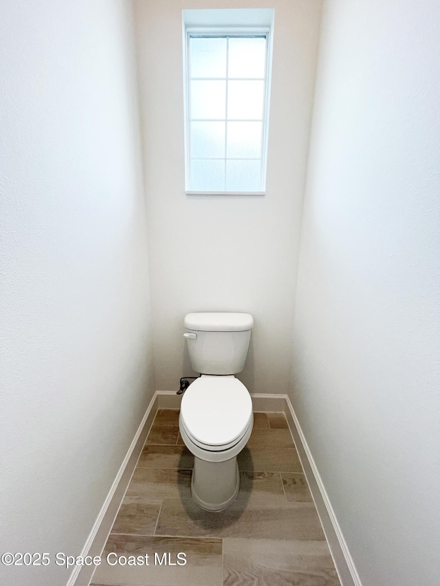 bathroom featuring toilet, baseboards, and wood finished floors