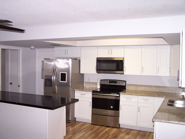 kitchen featuring white cabinets, dark wood-type flooring, stainless steel appliances, a textured ceiling, and a sink