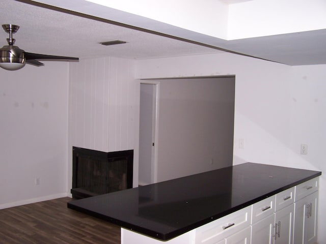 kitchen featuring a large fireplace, visible vents, white cabinets, dark countertops, and dark wood-type flooring