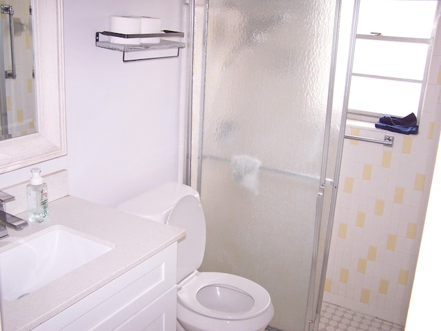 bathroom with vanity, a shower stall, and toilet