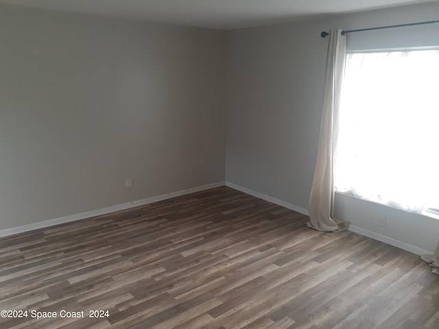 unfurnished room featuring dark wood-style flooring and baseboards