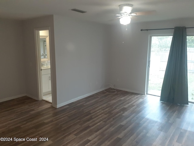 spare room with dark wood-style flooring, visible vents, and baseboards