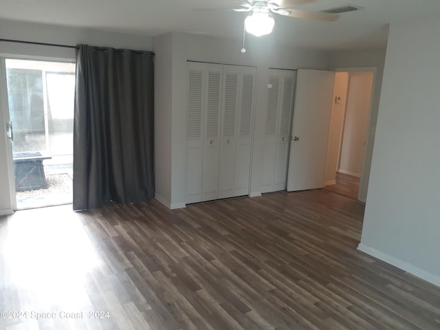 unfurnished bedroom featuring baseboards, visible vents, wood finished floors, access to exterior, and two closets