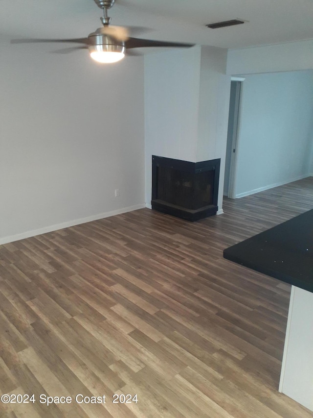 unfurnished living room featuring a fireplace, wood finished floors, visible vents, and baseboards