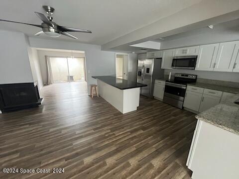 kitchen with ceiling fan, stainless steel appliances, dark wood-type flooring, and white cabinets