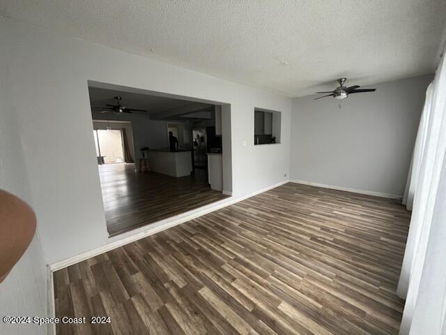 empty room featuring a ceiling fan, a textured ceiling, baseboards, and wood finished floors