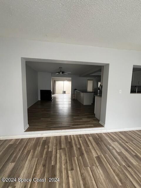 interior space featuring ceiling fan, a textured ceiling, baseboards, and wood finished floors