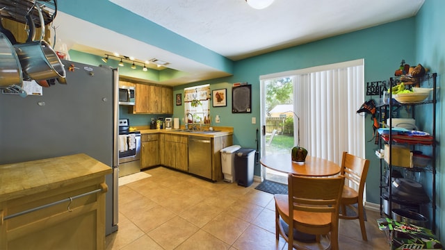 kitchen with sink, light tile patterned floors, track lighting, and appliances with stainless steel finishes