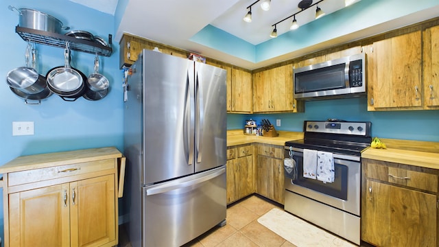 kitchen featuring light tile patterned flooring, appliances with stainless steel finishes, and butcher block countertops