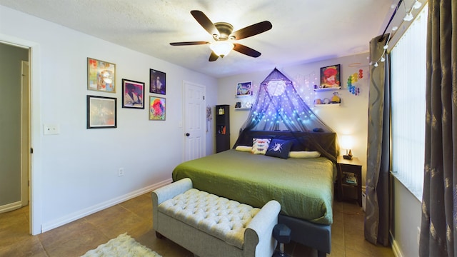 bedroom featuring ceiling fan, tile patterned flooring, and a textured ceiling