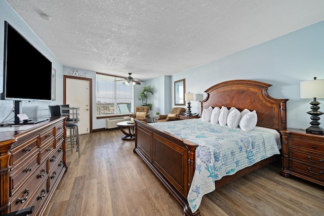 bedroom with wood-type flooring, a textured ceiling, and an AC wall unit