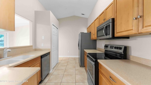 kitchen with lofted ceiling, appliances with stainless steel finishes, light tile patterned floors, and sink